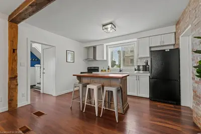 a kitchen with white cabinets and a black refrigerator at 4 Bedroom Luxury House, Free Parking, Next to LRT, Kitchener Downtown, near Chicopee Ski Club in Kitchener