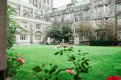 a large building with a green yard with flowers at Knox Residence - University of Toronto in Toronto
