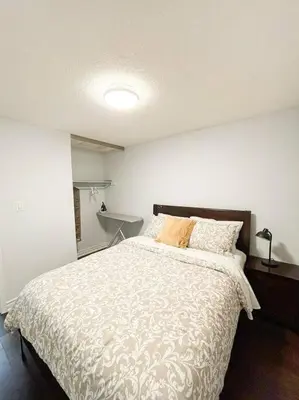 a bedroom with a large bed with a white comforter at Supreme Suites in Ajax