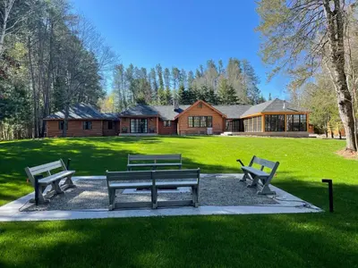 three benches sitting in a park in front of a house at Haliburton Post House in Minden