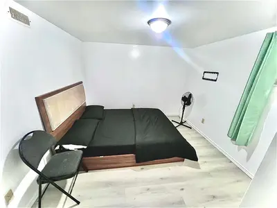 a bedroom with a black bed and a chair at Private Room Near Airport D7 in Brampton