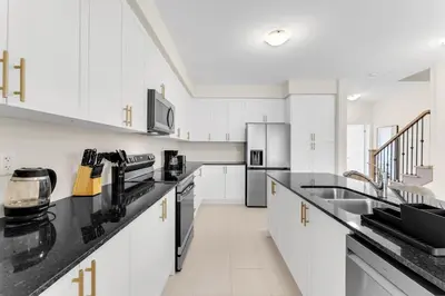 a kitchen with white cabinets and black counter tops at Bright & Stylish Modern Townhome in Oakville! in Oakville