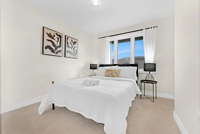 a white bedroom with a large bed and a window at Bright & Stylish Modern Townhome in Oakville! in Oakville