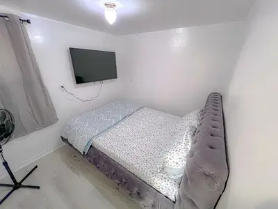 a small bedroom with a bed and a flat screen tv at Private Room Near Airport D4 in Brampton