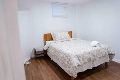 a bedroom with a bed with a white comforter at Adorable 3 Bedroom Apartment with Free Parking in Ajax