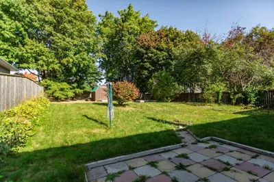 a yard with a fence and green grass and trees at Charming 4BR Barrie Retreat with Backyard in Barrie