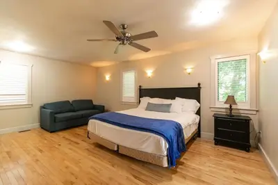 a bedroom with a bed and a fan and a couch at 5BR Riverfront Retreat w Firetable BBQ and Deck in Orangeville