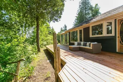 a wooden deck with a couch on a house at 5BR Riverfront Retreat w Firetable BBQ and Deck in Orangeville