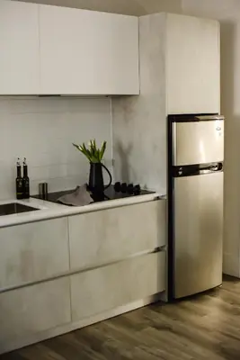 a kitchen with a stainless steel refrigerator and white cabinets at The VanderMarck Boutique Hotel in Collingwood