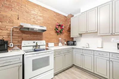 a kitchen with white appliances and a brick wall at Boutique 2BR Apartment on James St North Sleeps 6 in Hamilton