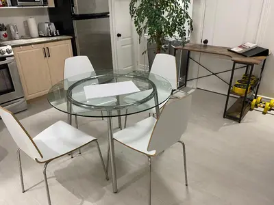 a glass table and white chairs in a kitchen at Akhtar's Residence in Mississauga