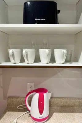a red and white tea kettle on a shelf with cups at Super Cosy Peaceful room with Garden view free Parking in Toronto