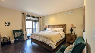 a bedroom with a bed and a desk and chairs at Niagara Creekside B&B - Waterfront suite in Niagara Falls