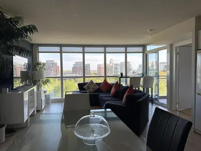 a living room with a couch and a table and some windows at LakeView 2Bdrms 2Baths with 3 real beds and parking in Toronto