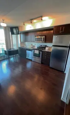 a kitchen with wooden floors and stainless steel appliances at Luxury Downtown Condo with CN tower views, Pool Access, Gym,Free Parking upon request at booking, accommodates 4 in Toronto