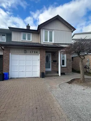 a house with a white garage door and a tree at Luxurious modern basement apartment in Pickering
