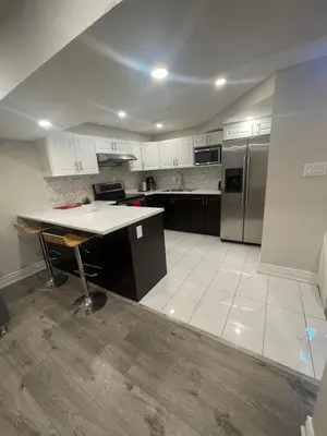 an empty kitchen with a table and a refrigerator at CozyHaven A private entrance, comfy basement apartment in Mississauga with free parking Conveniently located with easy access to the airport downtown Toronto major malls and highways for a seamless stay in Mississauga