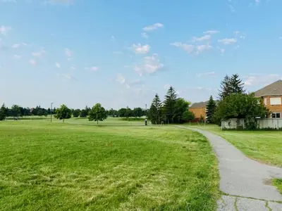 a grassy field with a path leading to a house at Sunnys Home Stays TorontoMississauga Pvt Entrance 2B'Rm Bath Living & Kitchen in Mississauga