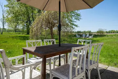 a wooden table with white chairs and an umbrella at Field of Dreams in Bloomfield