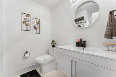 a white bathroom with a toilet and a mirror at NEW Stylish 1BR Apartment With BBQ and Situated Close to the Falls and Can Sleep 4 Guests in Niagara Falls