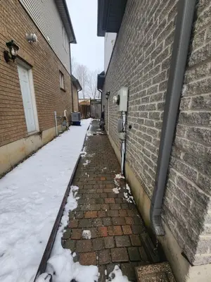 a brick alley with snow next to a building at The Cozy Den in Ingersoll