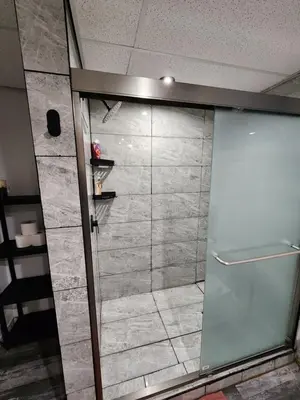 a shower with a glass door in a room at The Cozy Den in Ingersoll