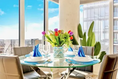 a glass dining table with chairs and flowers on it at High Rise 1BR Building w Gorgeous Views in Kitchener