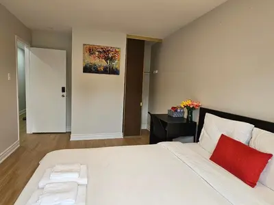 a bedroom with a large white bed with a red pillow at A Home Away-Cozy Guest Room in Toronto in Toronto