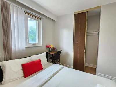 a bedroom with a white bed with a red pillow at A Home Away-Cozy Guest Room in Toronto in Toronto