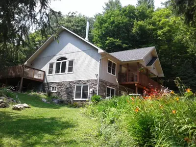 a stone house with a porch and a deck at Stone Ridge Chalet Bed n Breakfast in Dorset