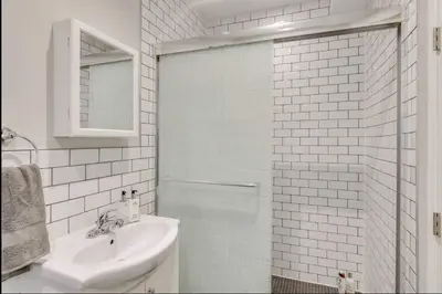 a white bathroom with a sink and a shower at Casa Queen - Unique 2BR Suite in Leslieville in Toronto