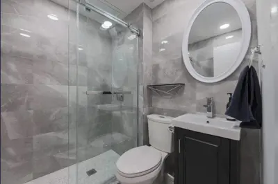 a bathroom with a shower and a toilet and a sink at Casa Queen East - Modern 2BR Suite in Leslieville in Toronto