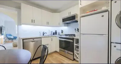 a kitchen with white cabinets and a white refrigerator at Casa Queen East - Modern 2BR Suite in Leslieville in Toronto