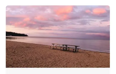 a picnic table on a beach with the ocean at Beautiful Apartment 5 mins from Innisfil Beach in Innisfil