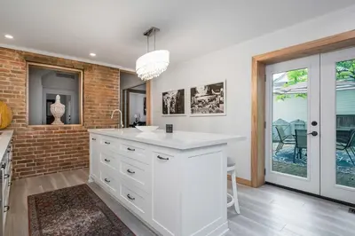 a kitchen with white cabinets and a brick wall at 3bed 2bath heritage duplex - Prime Location in Collingwood