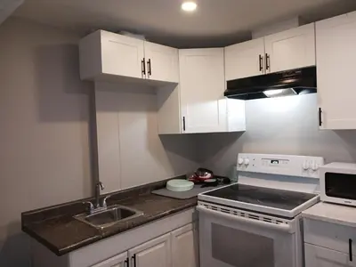 a kitchen with white cabinets and a sink and a stove at CheapSleep Room Near Kitchener Airport- 24X7 Checkin in Kitchener