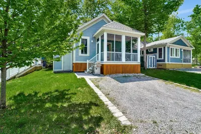 a small blue house with a porch and a driveway at The Chickadee - 21 Farm View in Cherry Valley