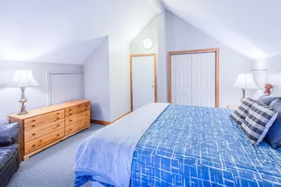 a bedroom with a blue bed and a couch at Relax at The Mountaintop Chalet in Blue Mountains