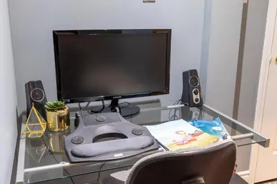 a glass desk with a computer monitor and speakers at Affordable Private Suite, Near Airport, Free Parking in Mississauga