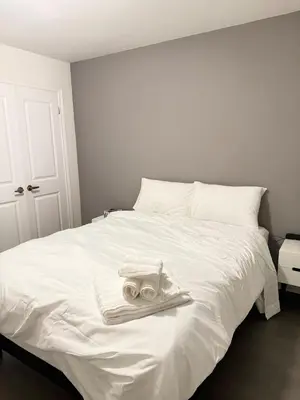 a white bed with two white towels on it at 4-Bdrm Comfort with Fireplace mins from Downtown in Port Colborne