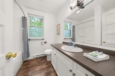 a white bathroom with a sink and a mirror at The Trillium - 2 Pine Forest in Cherry Valley