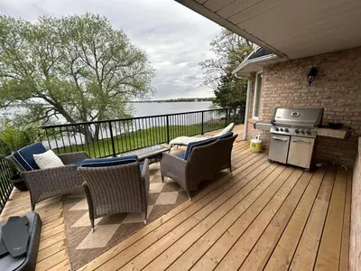 a deck with a grill and chairs and a stove at Comfy Waterfront Suite 2 Double Beds Ensuite in Belleville