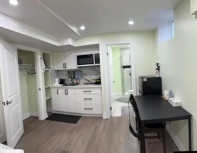 a kitchen with white cabinets and a black table at B1 Beautiful and cozy private suite in Mississauga