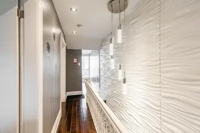 a hallway with white walls and wood floors and a staircase at Modern City Suite with Rooftop Patios in Toronto
