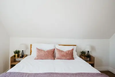a bedroom with a white bed with pink pillows at Park and Mill - Hot Tub and Bocce Court in Bloomfield