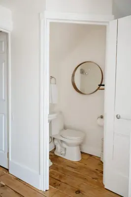 a white bathroom with a toilet and a mirror at Park and Mill - Hot Tub and Bocce Court in Bloomfield