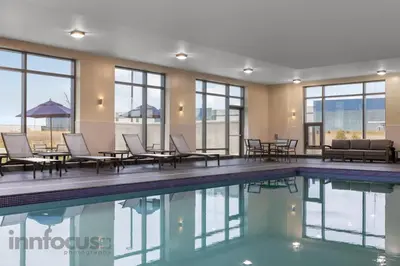 a pool with chairs and tables in a building at Hyatt Place Mississauga / Airport Corp Center in Mississauga