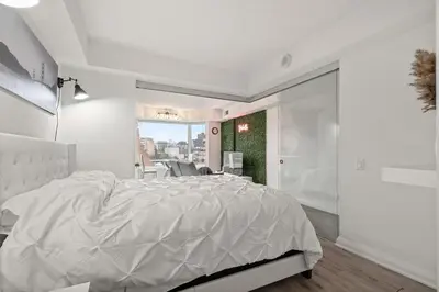 a white bedroom with a large bed and a window at Luxurious Suite in Yorkville in Toronto