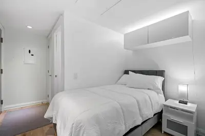 a white bedroom with a bed and a night stand at Luxurious Suite in Yorkville in Toronto