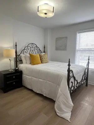 a bedroom with a large bed with white sheets and yellow pillows at St Catharines Niagara Escape in St. Catharines